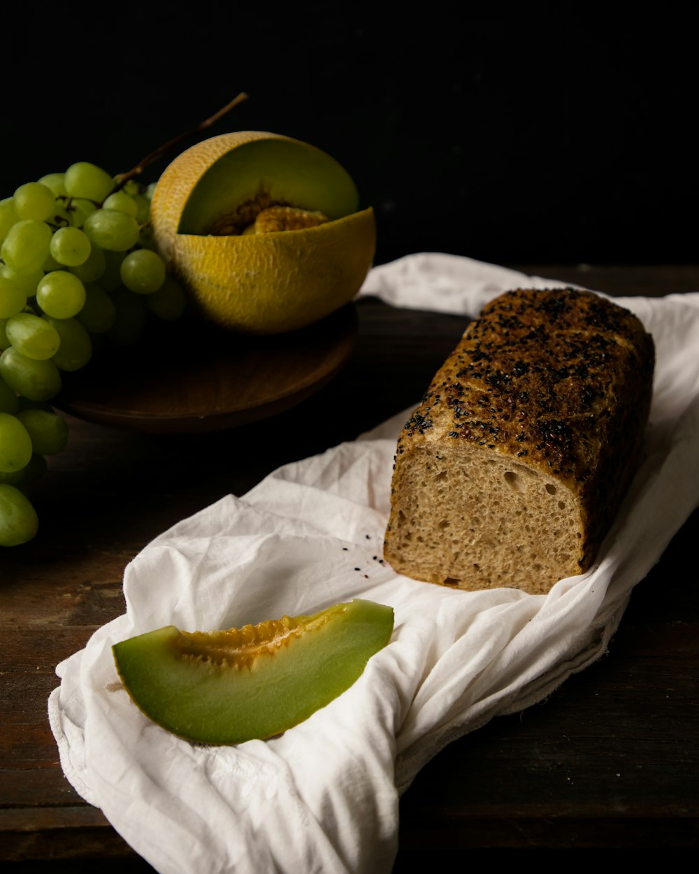 a loaf of bread sitting on top of a table next to grapes