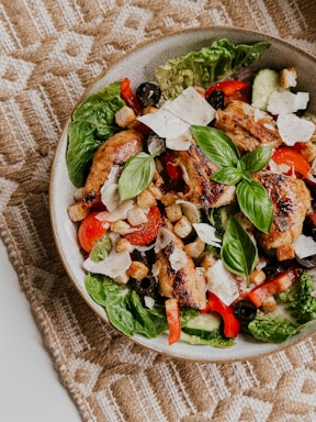 A vibrant, colorful dish of a quick, healthy salad with fresh vegetables and grilled chicken on a rustic wooden table.