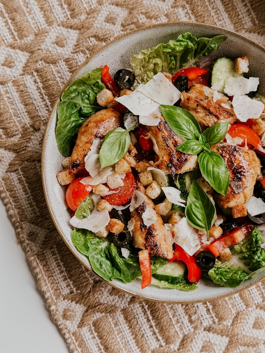 A vibrant, colorful dish of a quick, healthy salad with fresh vegetables and grilled chicken on a rustic wooden table.