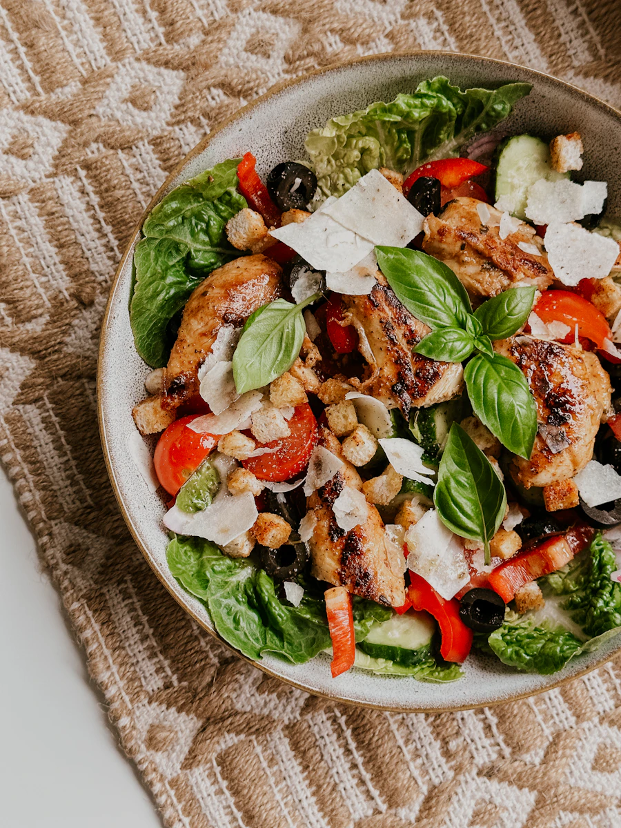 A fresh salad with chicken, tomato, olives and cheese