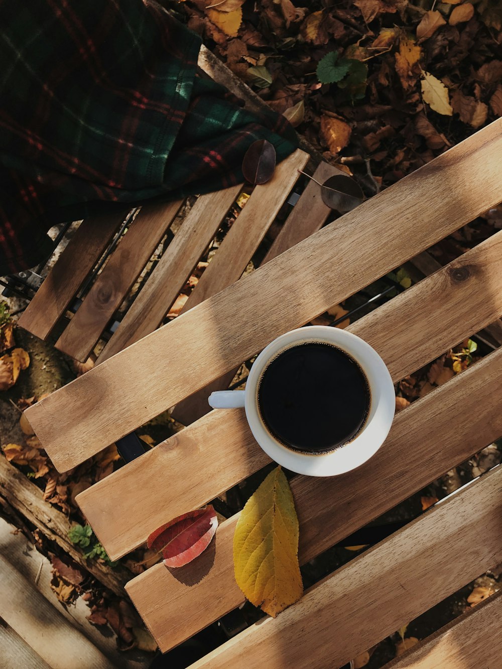 a cup of coffee sitting on top of a wooden bench