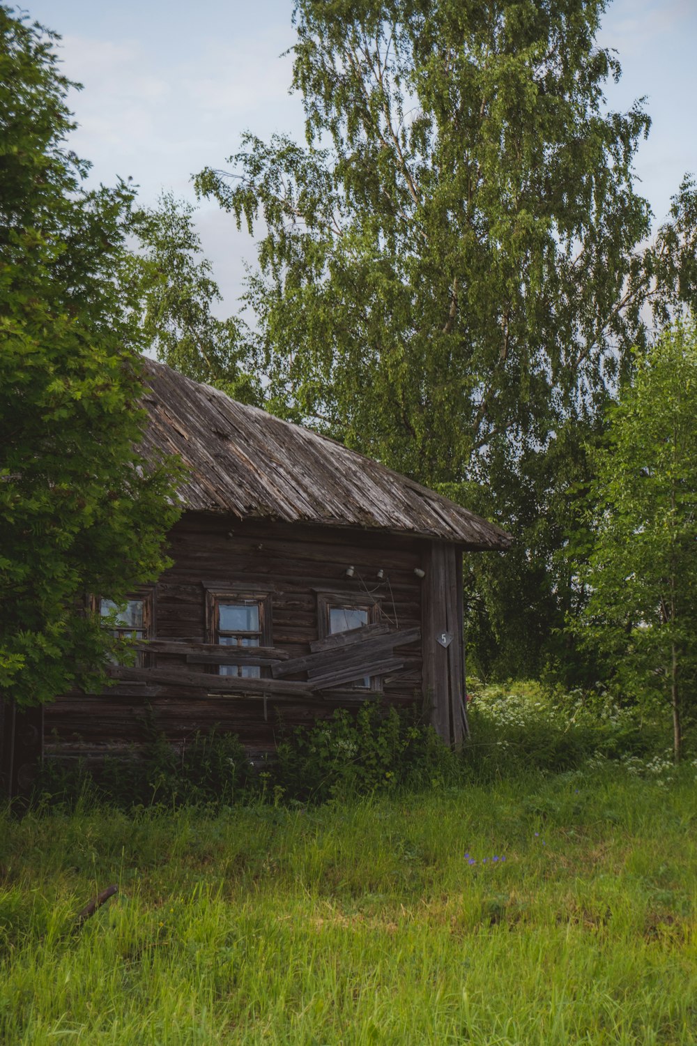 an old log cabin in a field with trees in the background