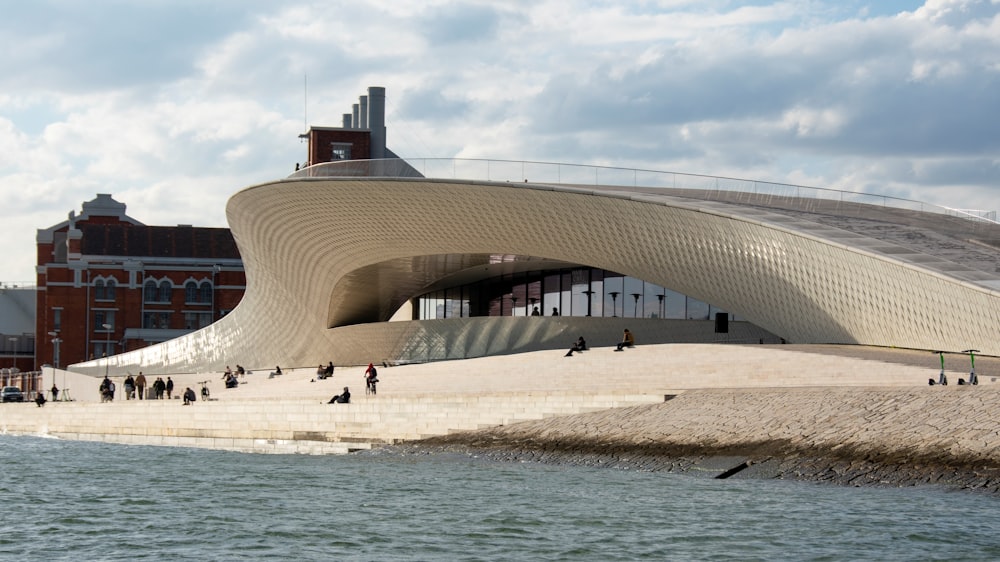 a building with a curved roof next to a body of water