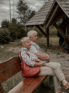 a man and a woman sitting on a wooden bench