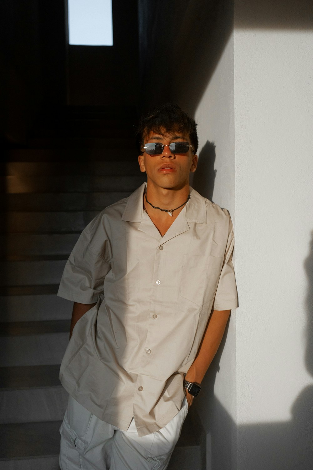 a man in sunglasses leaning against a wall