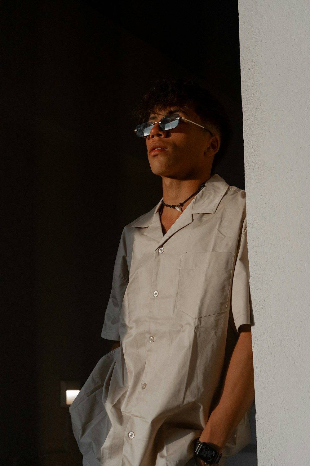 a man wearing sunglasses standing next to a wall