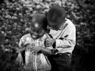 A candid moment of siblings hugging each other while playing with natural wooden toys.