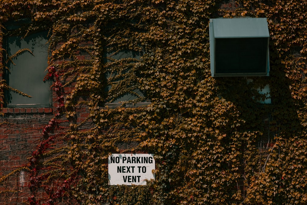 a brick building covered in vines and a no parking sign