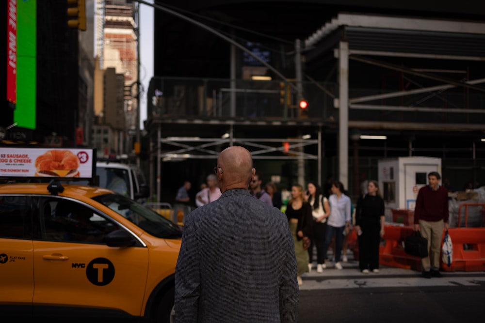 a man walking across a street next to a yellow taxi