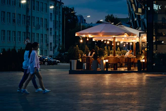 Happy customers enjoying their bowls and snacks outdoors under shaded umbrellas with warm lighting.