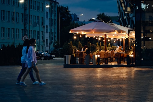 Modern restaurant patio with diners enjoying meals under warm lighting.