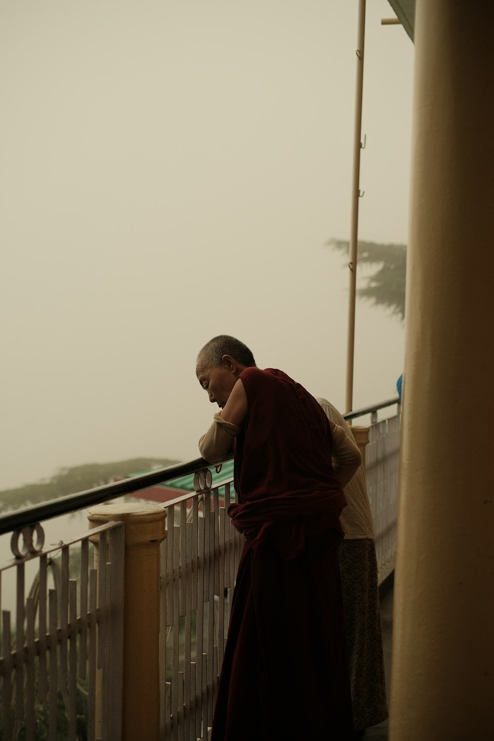 a monk standing on a balcony next to a railing