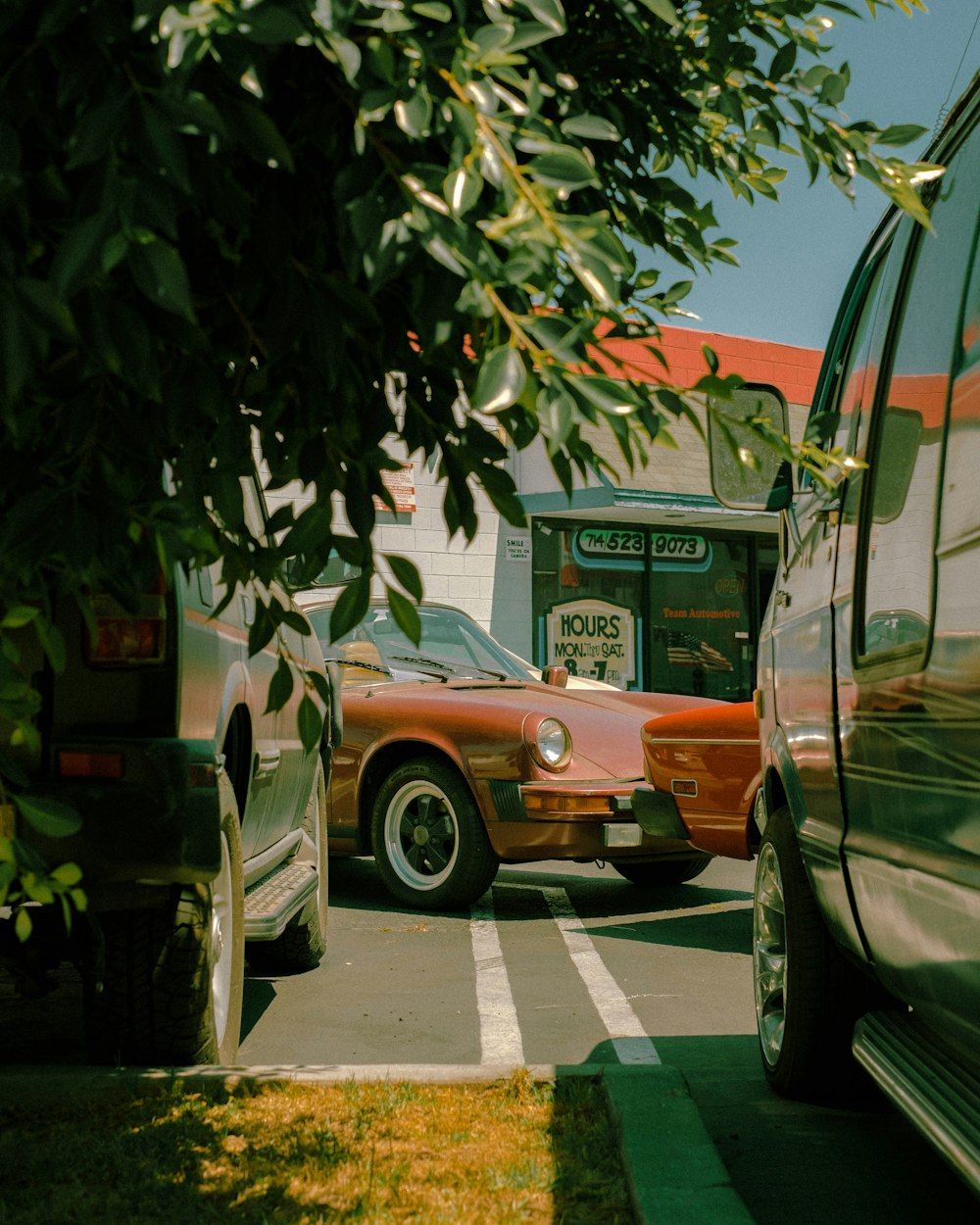 a red car parked in a parking lot next to a bus