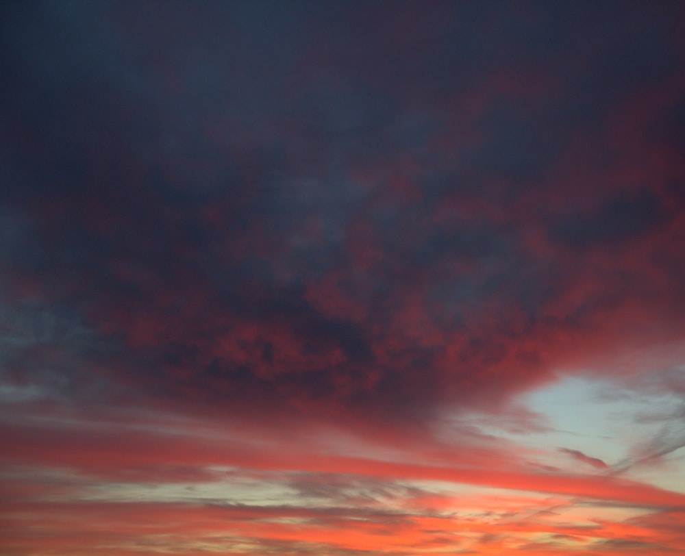 a plane flying in the sky with a sunset in the background