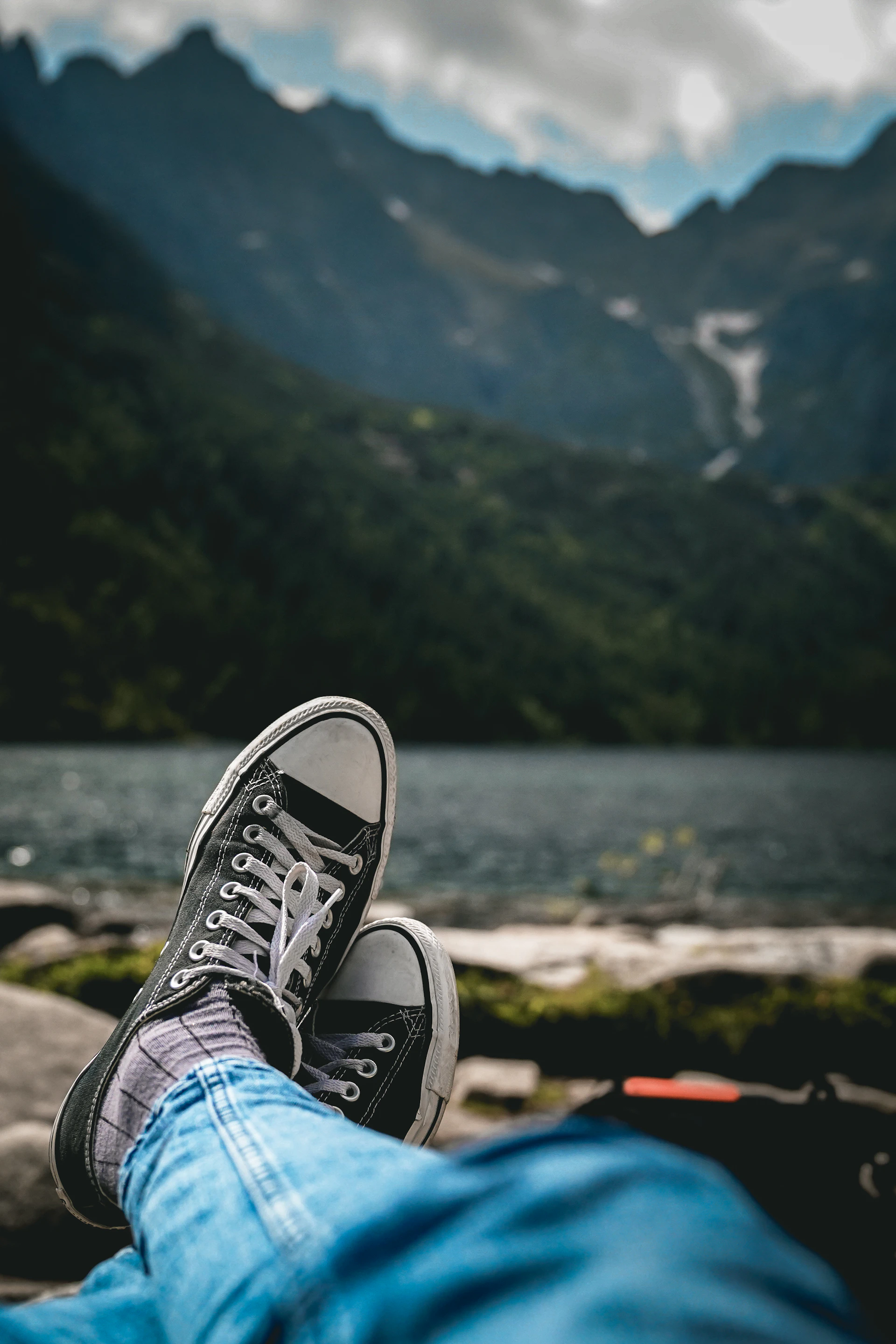 Casual sneakers showcased on a casual outfit worn by a smiling woman outdoors.
