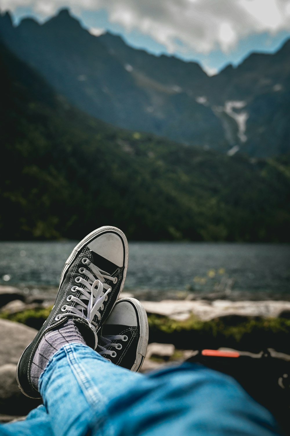 a person's feet resting on the ground with mountains in the background