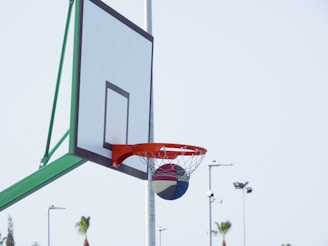 A basketball hoop with a Lift Athletics Inc ball swishing through the net on an outdoor court.