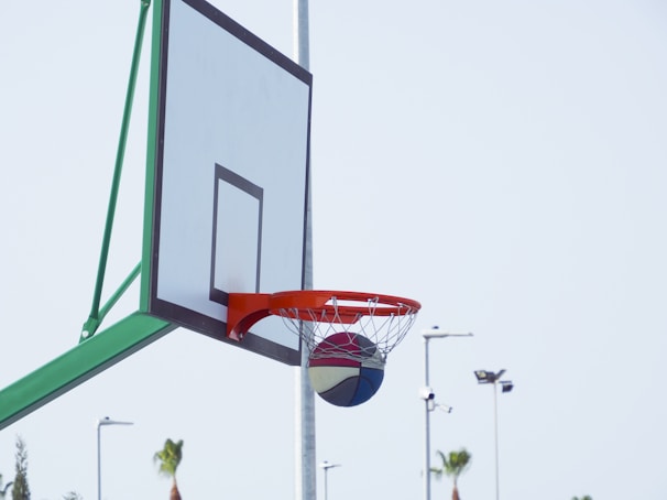 A basketball hoop with a Lift Athletics Inc ball swishing through the net on an outdoor court.