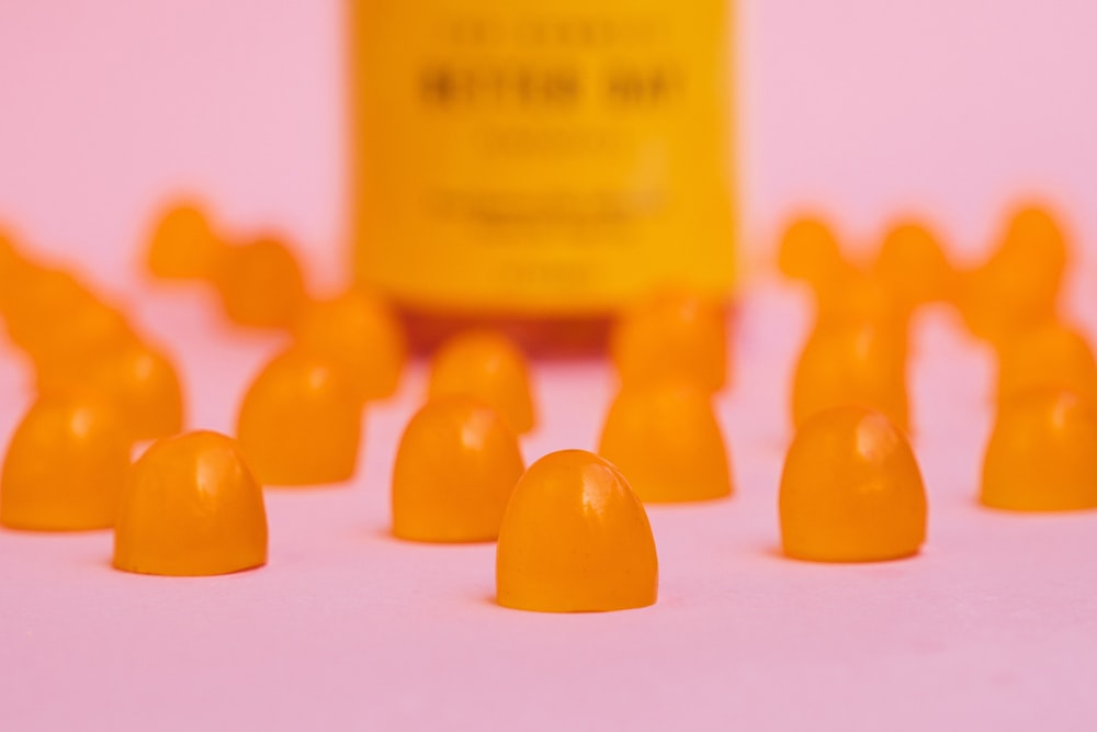 a group of orange candies sitting next to a bottle