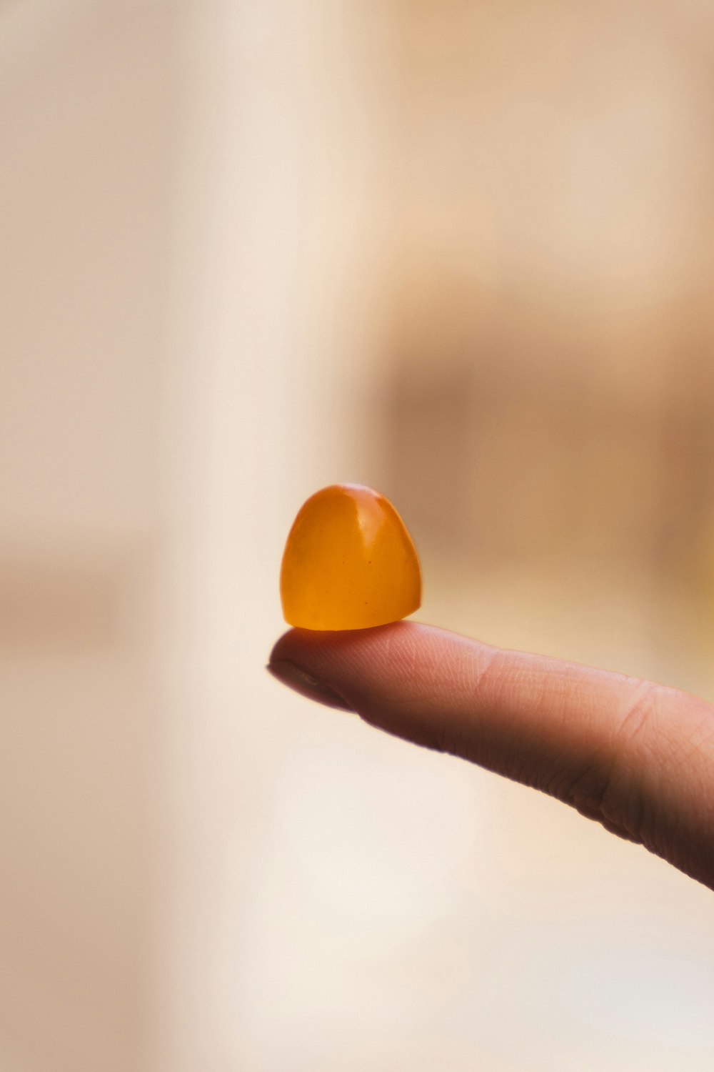 a hand holding a small orange object in it's palm