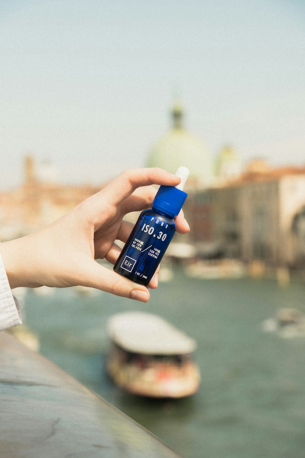 a person holding a bottle of water near a body of water