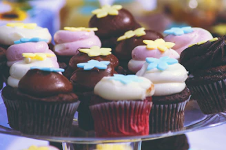 A colorful display of assorted cupcakes with sprinkles and frosting on a bakery counter.