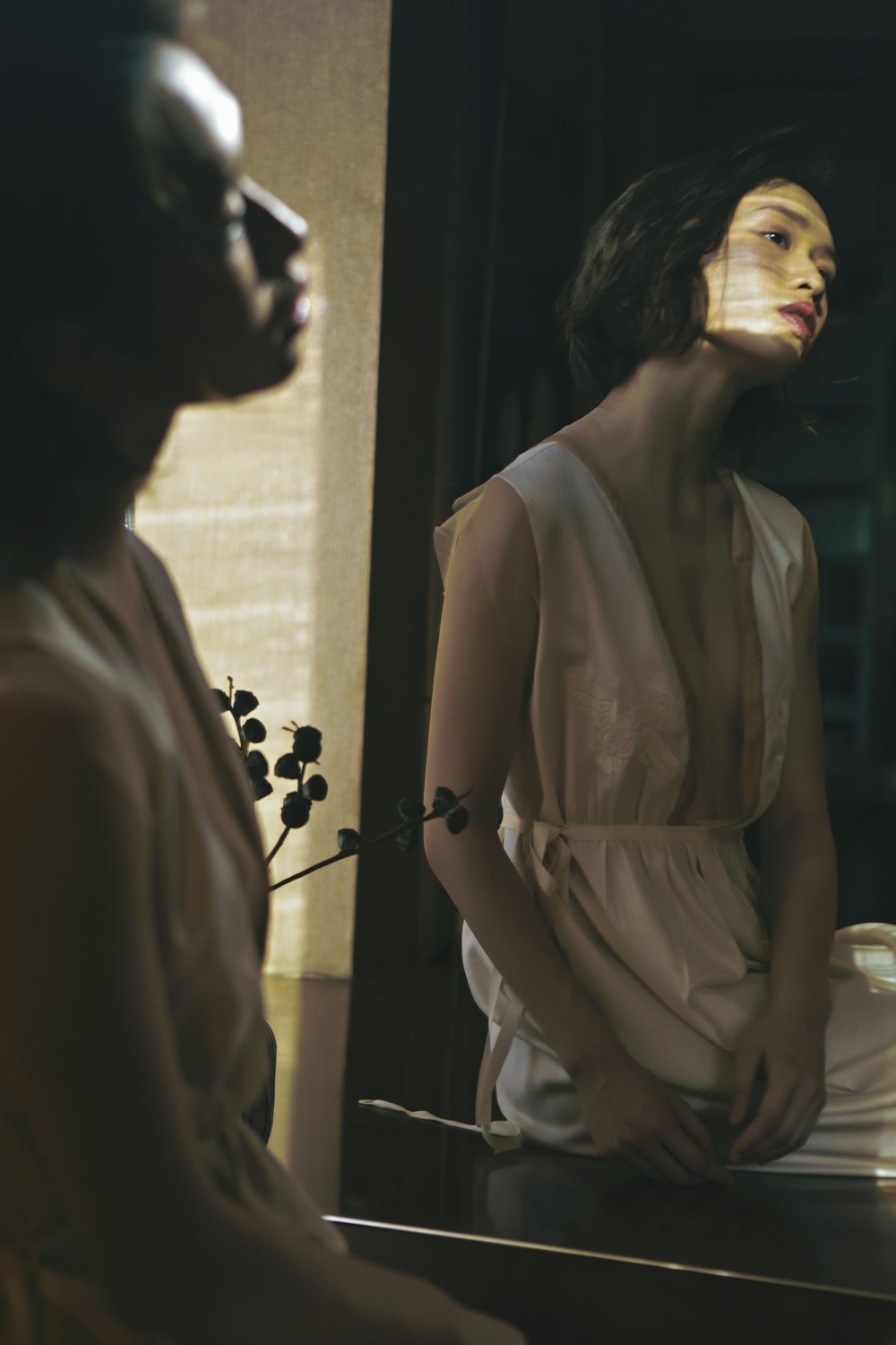 a woman in a white dress looking at herself in a mirror