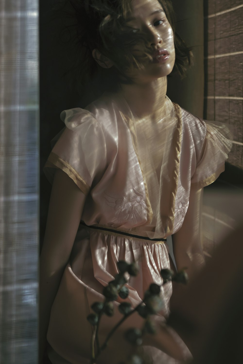 a woman in a pink dress standing next to a window