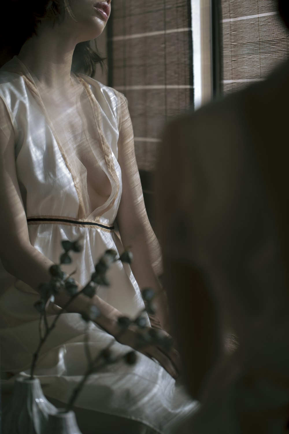 a woman in a white dress looking out a window