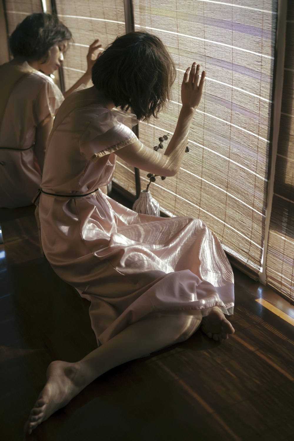 a woman sitting on the floor in front of a window