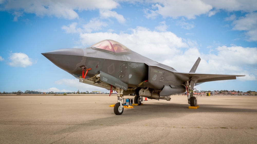 a fighter jet sitting on top of an airport tarmac