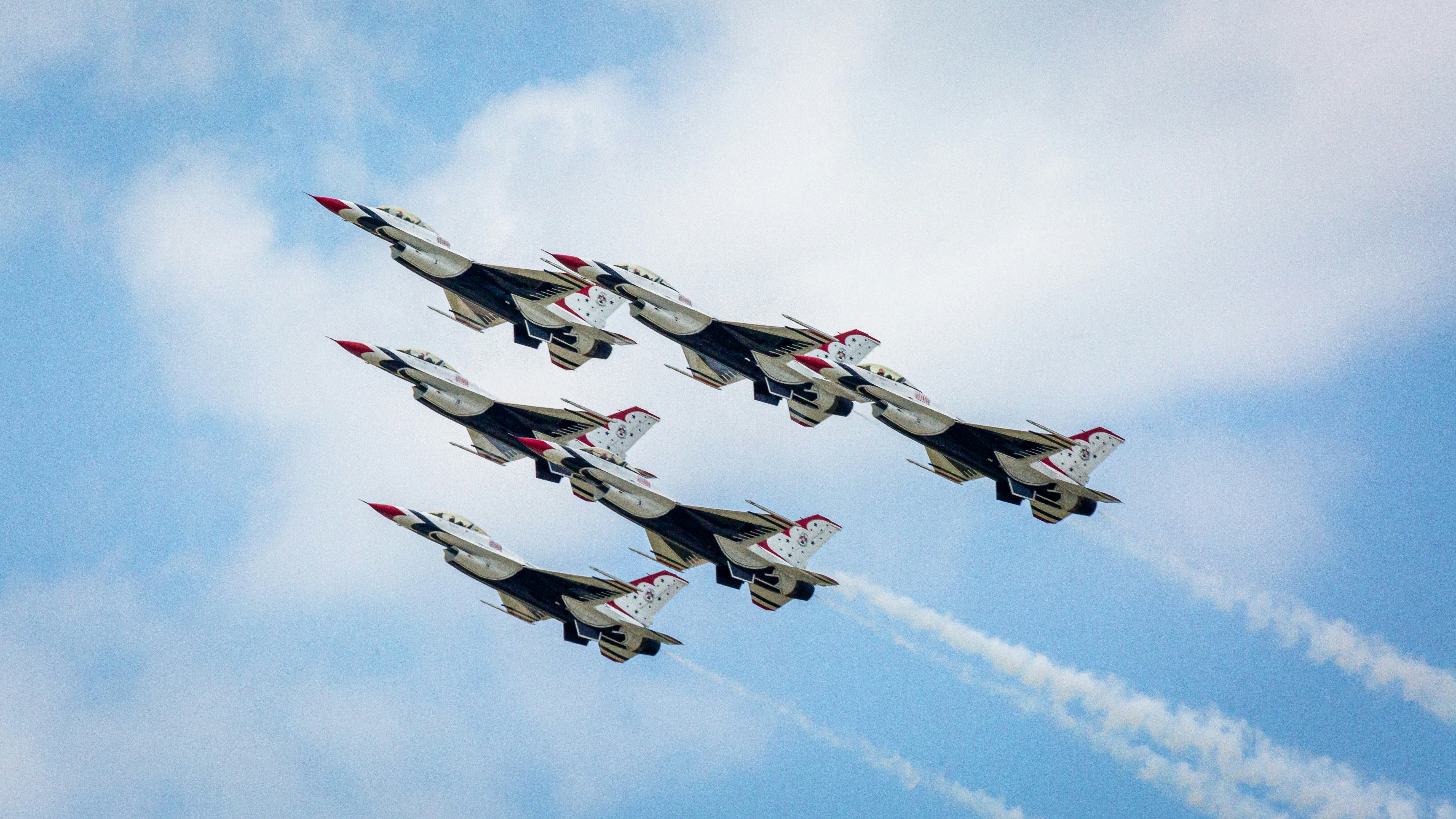a group of fighter jets flying through a blue sky, 