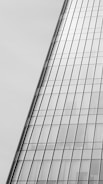 A modern glass skyscraper with reflective windows, featuring a sleek and angled design. The architectural lines are clean and precise, giving a sense of contemporary elegance.