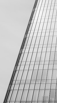 A modern glass skyscraper with reflective windows, featuring a sleek and angled design. The architectural lines are clean and precise, giving a sense of contemporary elegance.