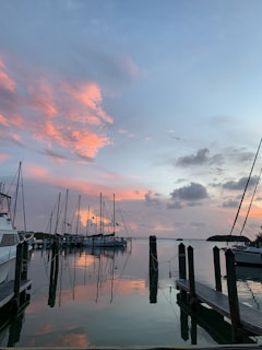 A serene marina with yachts docked along wooden piers at sunset.