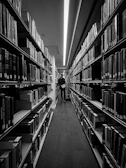 Black-and-white photograph of tall library shelves filled with worn books.