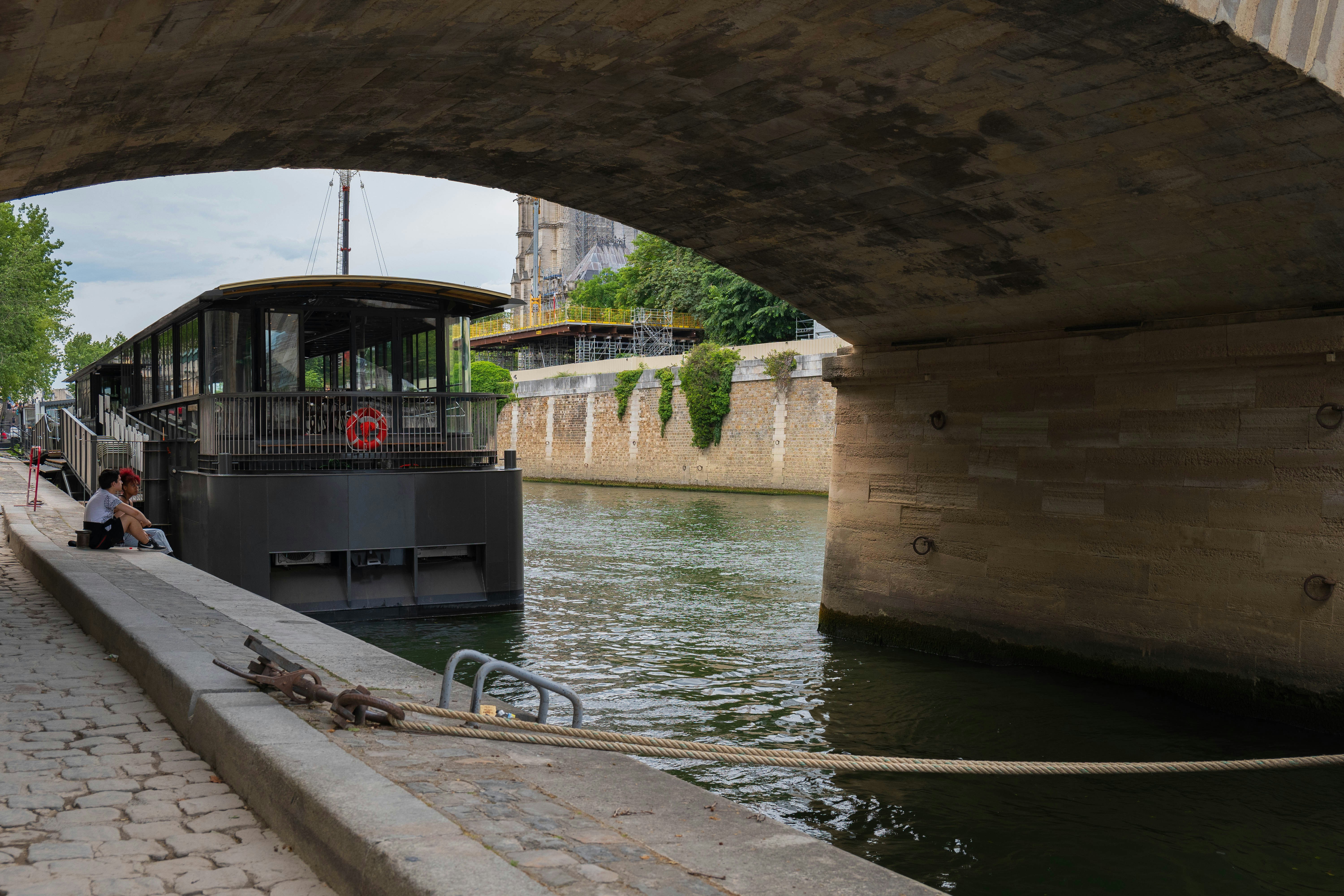 a boat traveling under a bridge next to a river