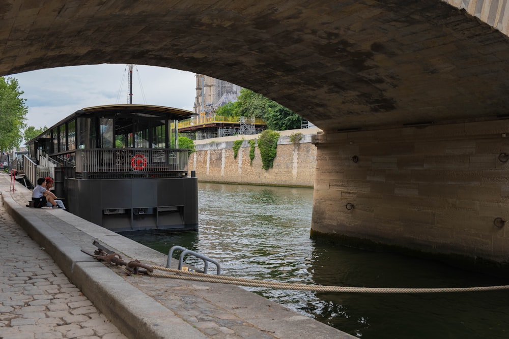 a boat traveling under a bridge next to a river