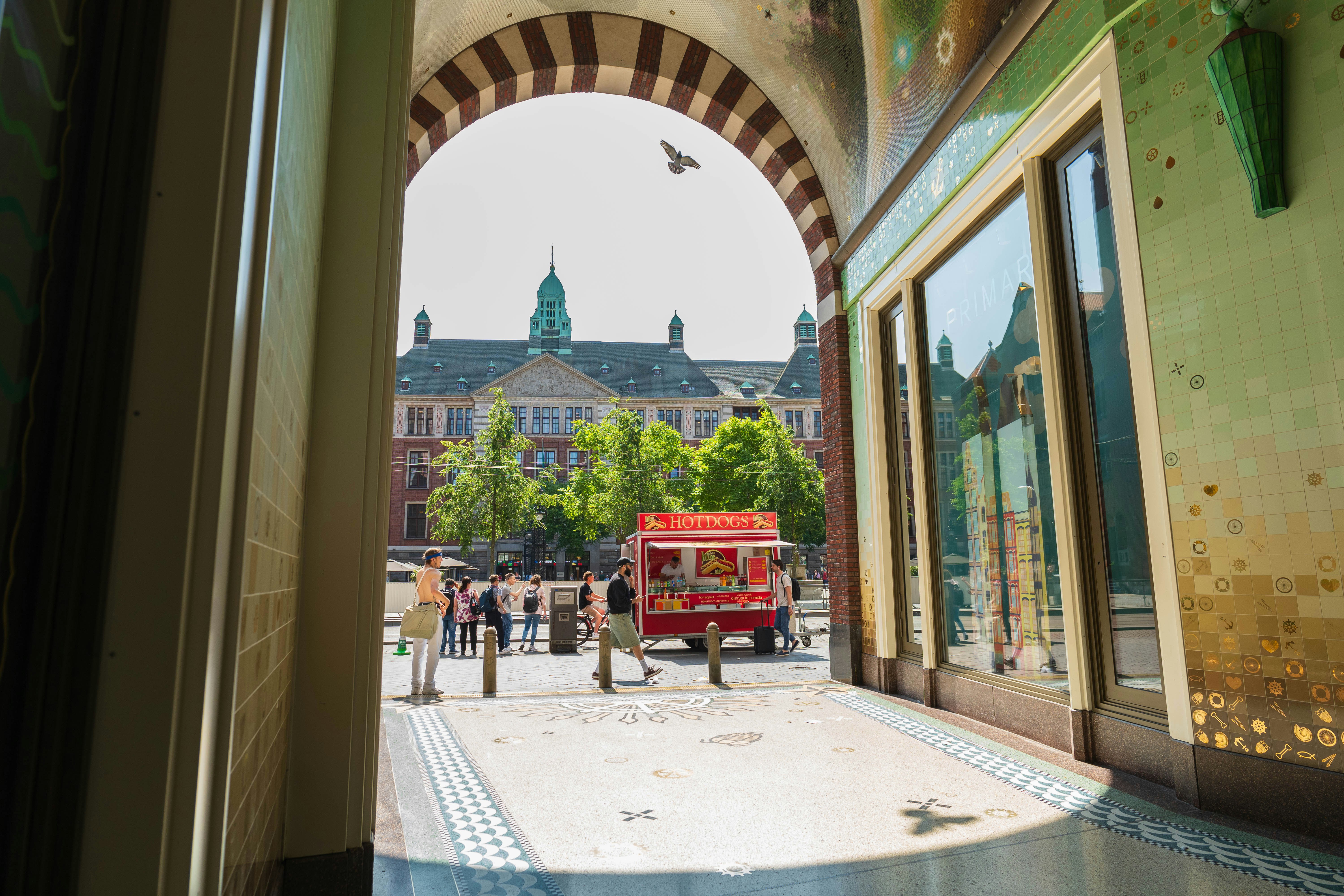 a red truck driving down a street next to a tall building