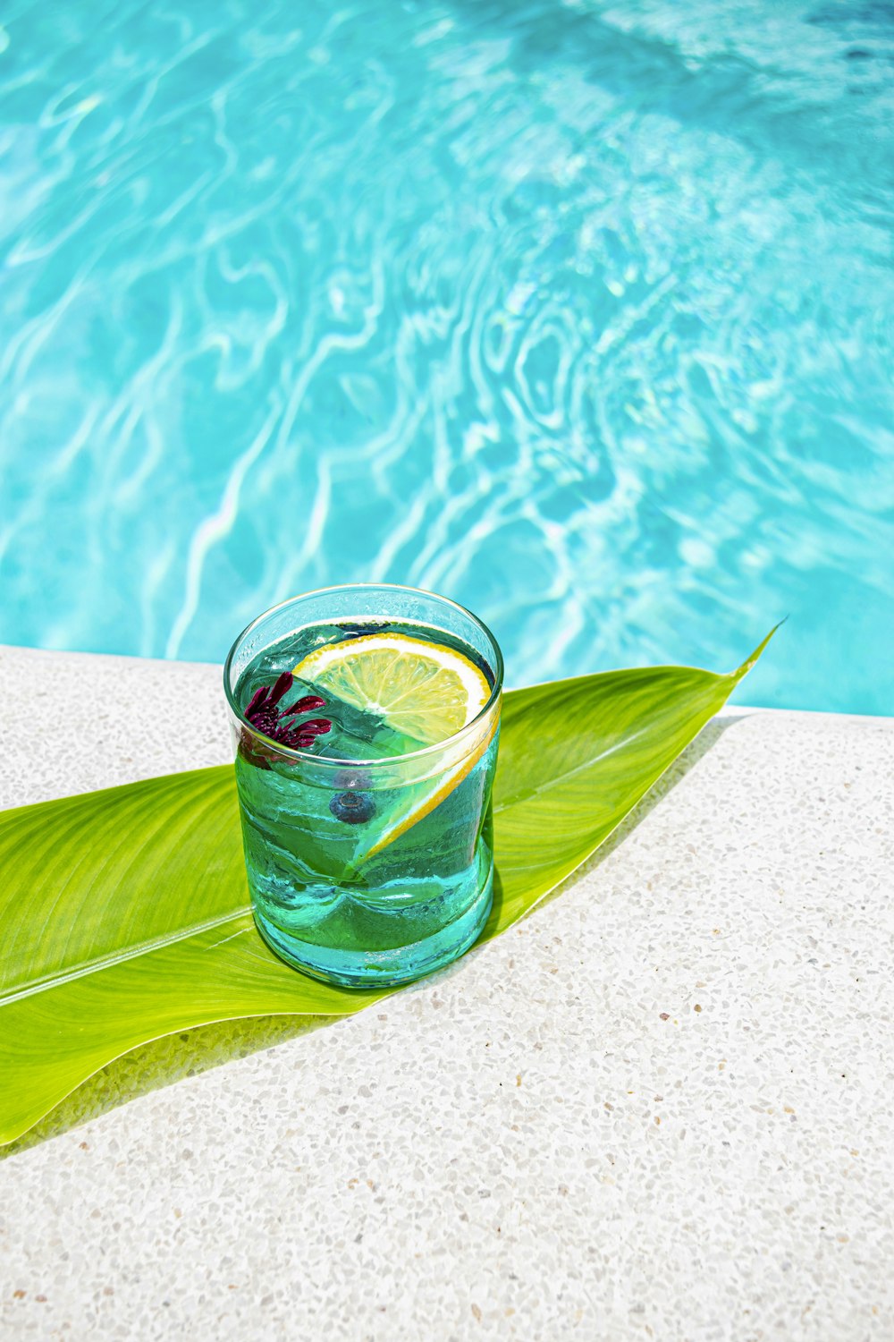 a glass of water sitting next to a pool