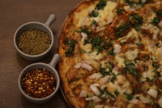 A close-up of a homemade pizza with fresh vegetables and herbs on a rustic wooden table