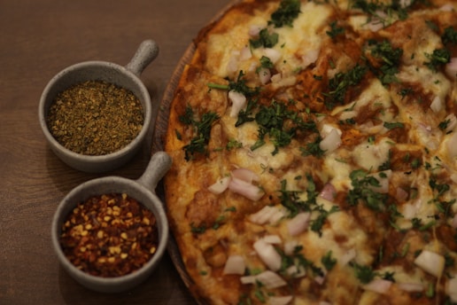 A close-up of a homemade pizza with fresh vegetables and herbs on a rustic wooden table