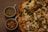 A close-up of a homemade pizza with fresh vegetables and herbs on a wooden table.