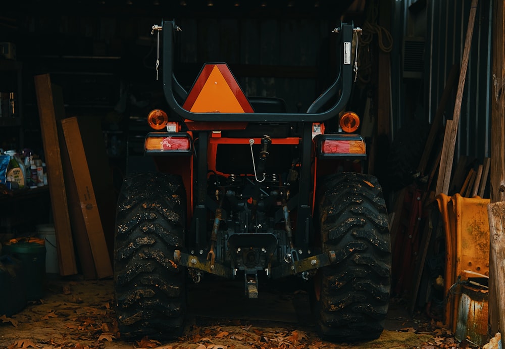 a tractor parked inside of a garage next to a pile of wood