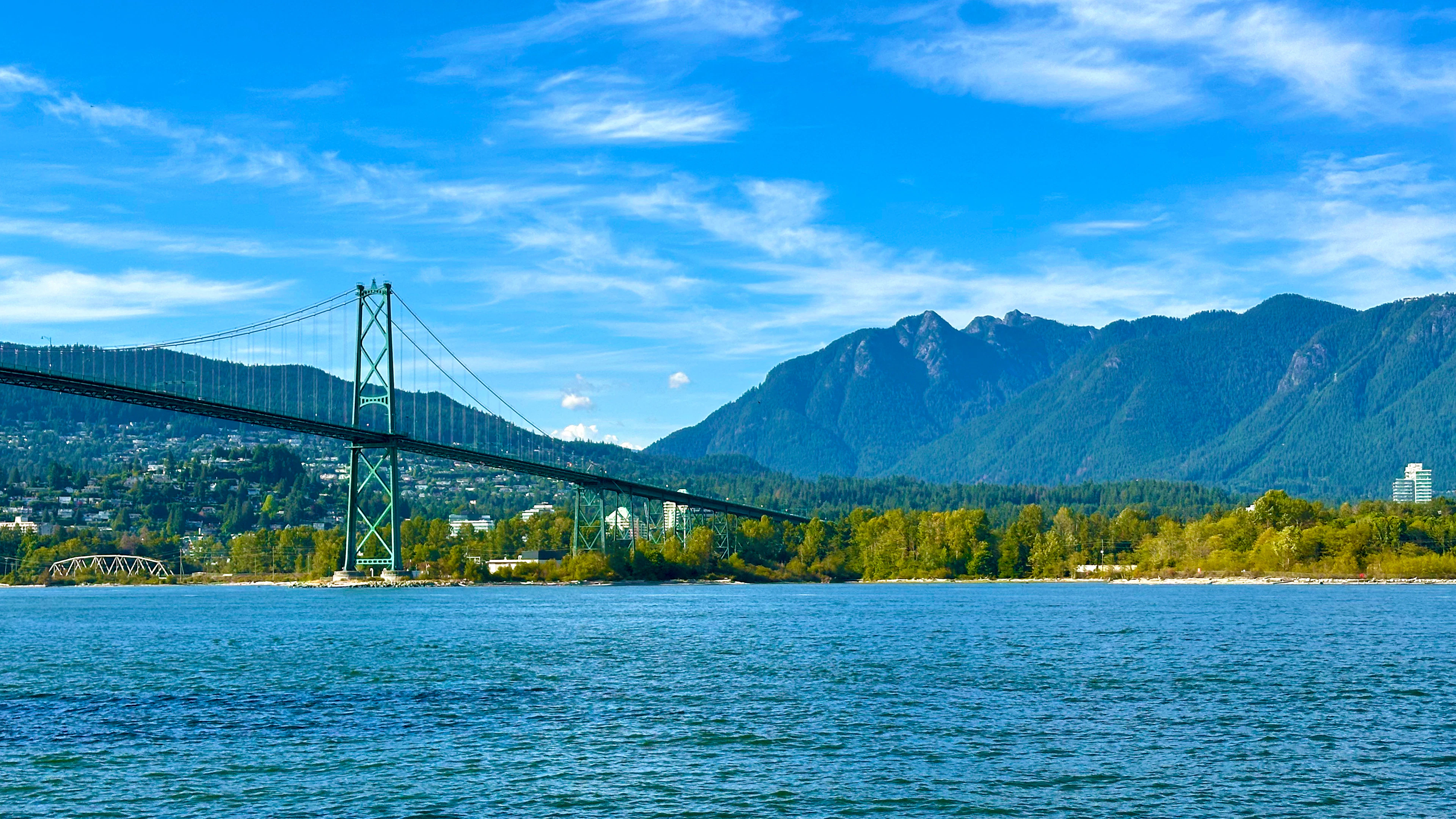 The Lions Gate Bridge spanning Burrard Inlet in Vancouver, with the forested North Shore mountains rising behind.