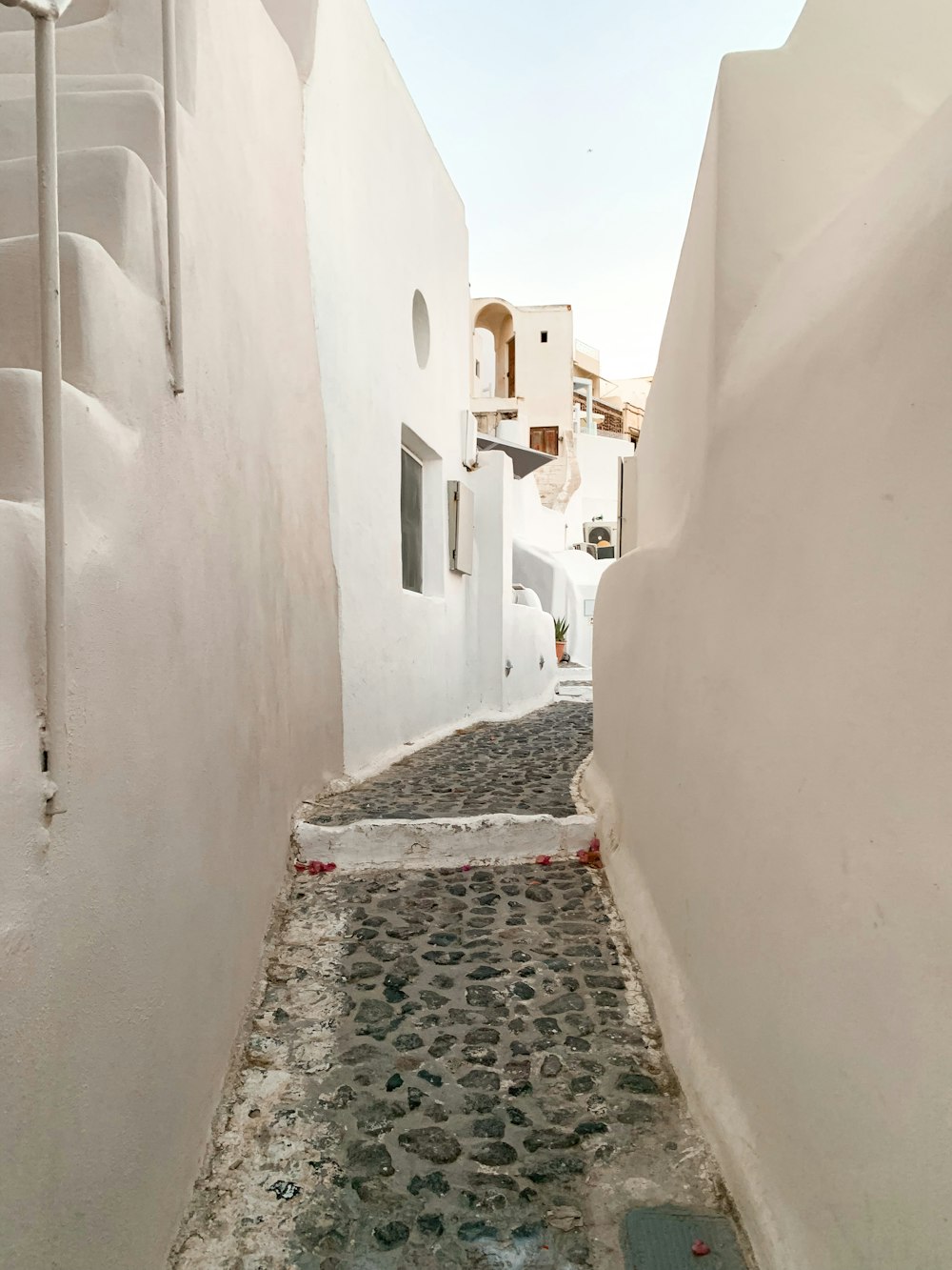 a narrow alley way with white walls and cobblestones