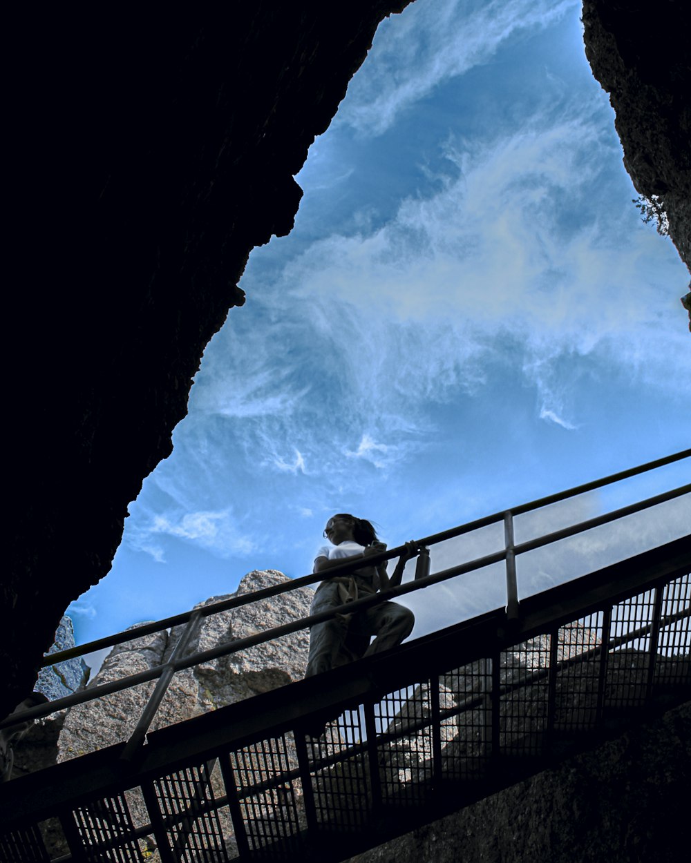 a person sitting on a railing looking up at the sky