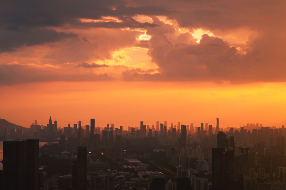 the sun is setting over a city with tall buildings