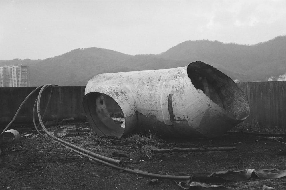 a large pipe laying on top of a field next to a fence