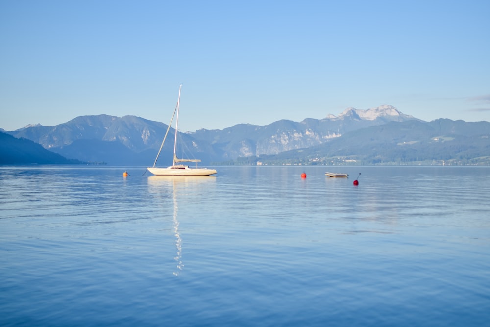 a sailboat floating on a lake with mountains in the background